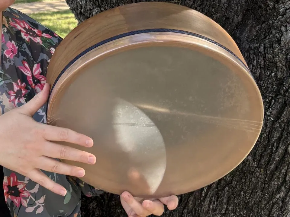 Two women holding large frame drums during a gathering